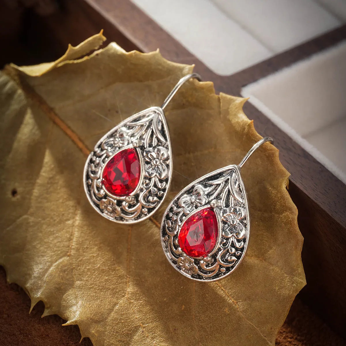 Pair of retro Bohemian carved drop earrings in red alloy for women, shown as a single pair