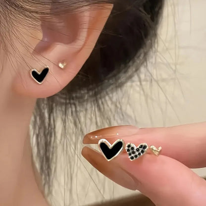 Three pairs of heart-shaped electroplated earrings in gold, black, black and white, and pink colours