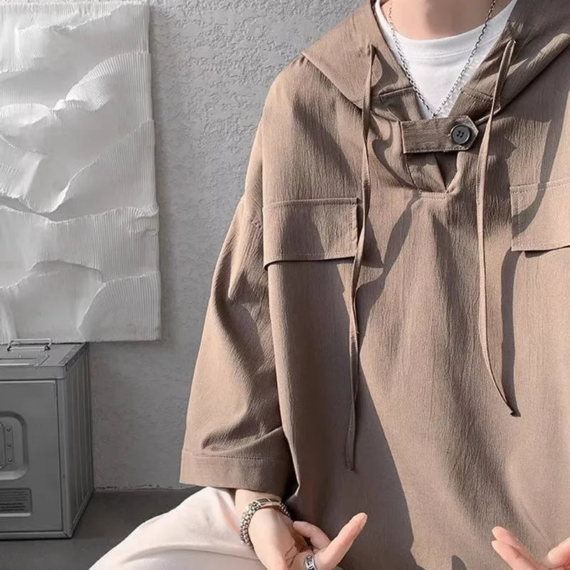 A man wearing a loose-fit black hooded short sleeve t-shirt for summer.