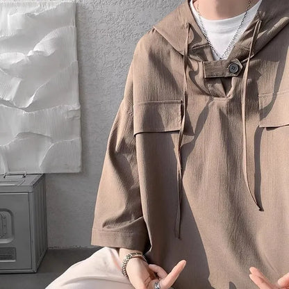 A man wearing a loose-fit black hooded short sleeve t-shirt for summer.