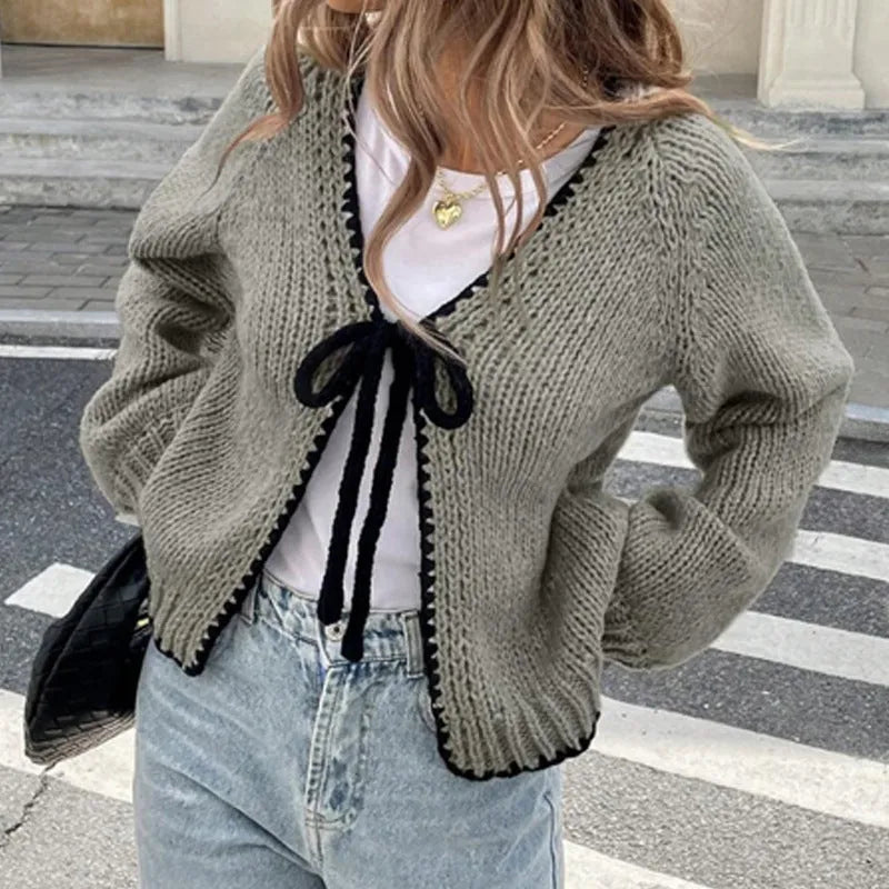 Loose grey lace-up front cardigan sweater with crocheted flower detail on a model.