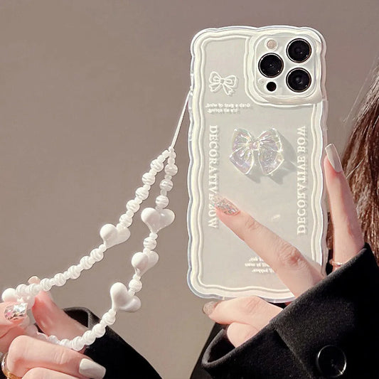 Transparent TPU iPhone case with 3D ice-through bow design on a mobile phone, showing optional white love lanyard attached.
