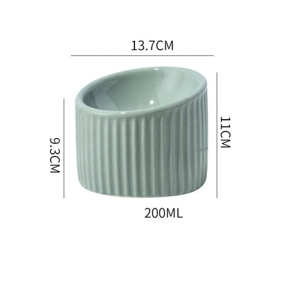 Ceramic raised cat bowl in light green, showing elevated tilted design for pet feeding.