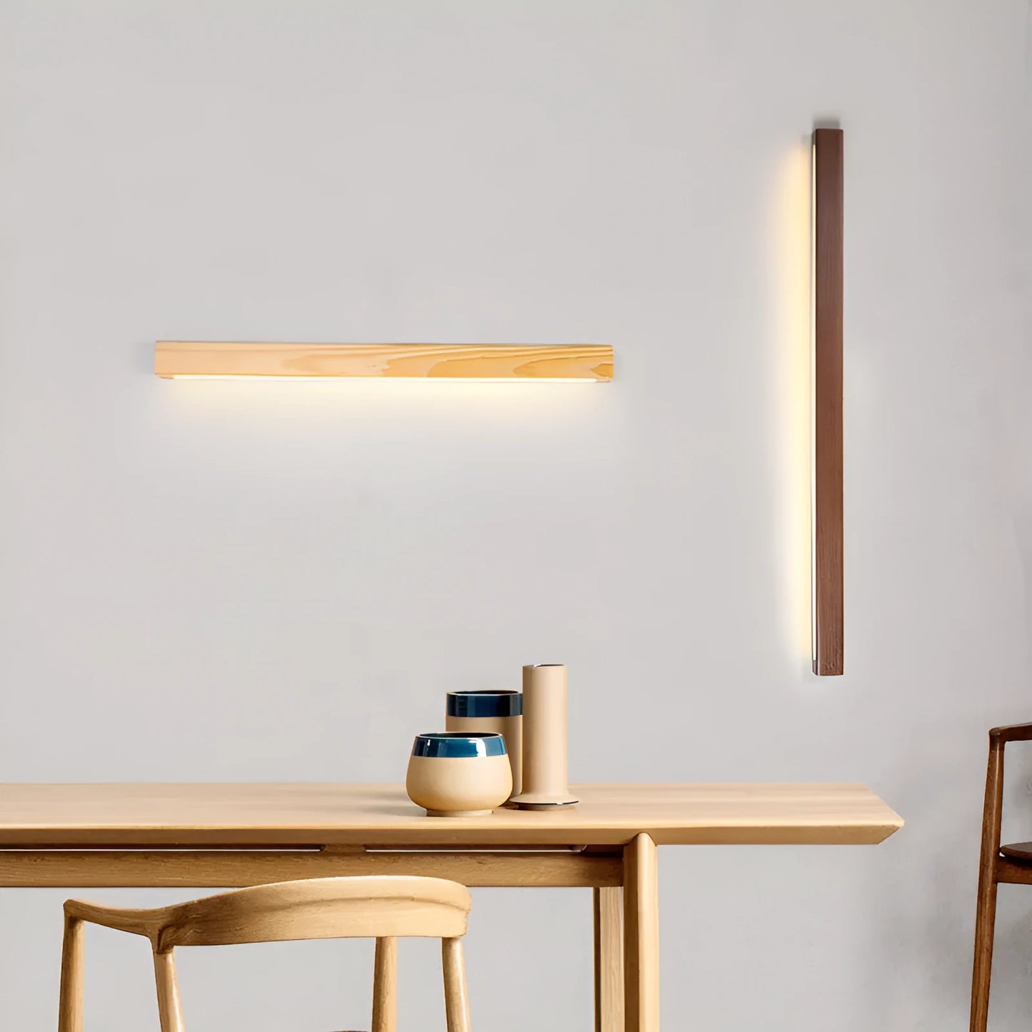 Slim walnut-colour wooden strip wall lamp with integrated LEDs mounted on a plain wall.