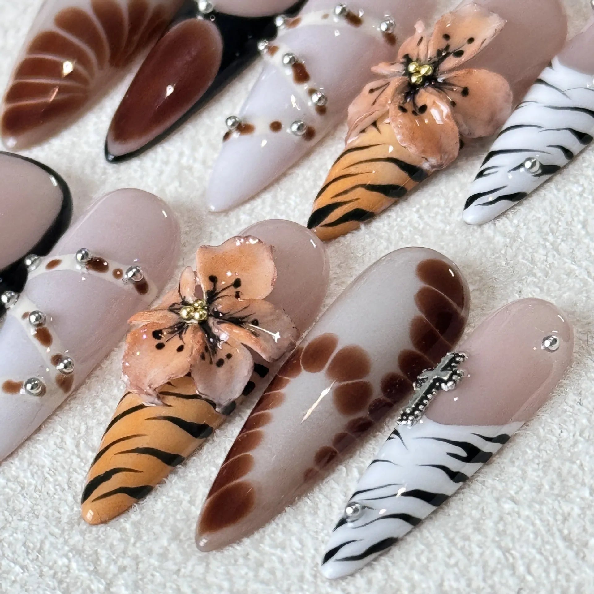 Set of ten leopard print, cross, and floral design press-on nail stickers in long-tip style on a white background.