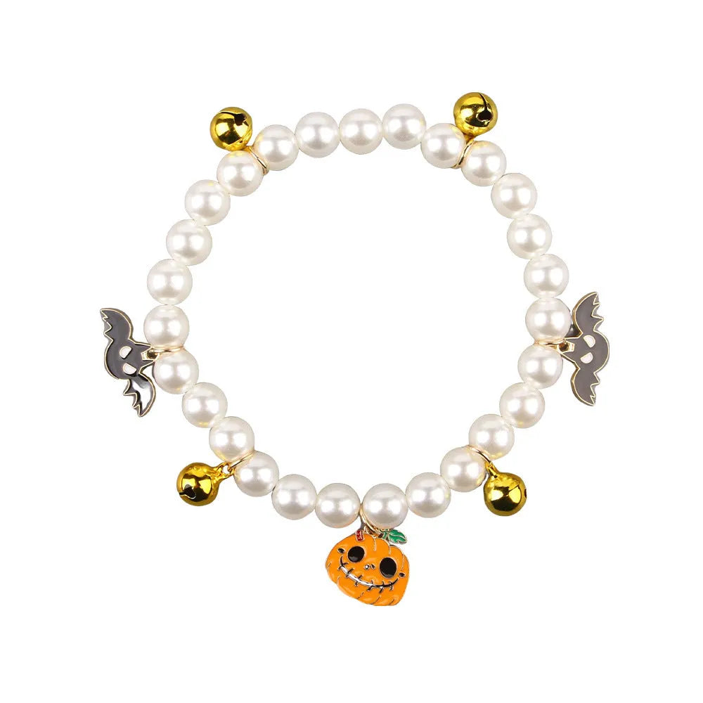 Three silver-tone pet necklaces with faux pearls and jingle bells laid flat on a surface.
