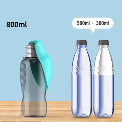 Blue grey portable dog water bottle with foldable drinking bowl and wrist strap, shown next to a dog.