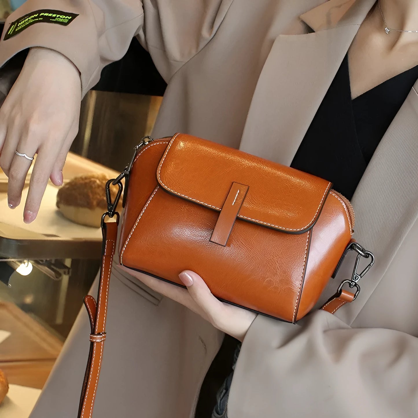 Women's brown shell-shaped genuine leather messenger bag with a single shoulder strap and visible stitching.