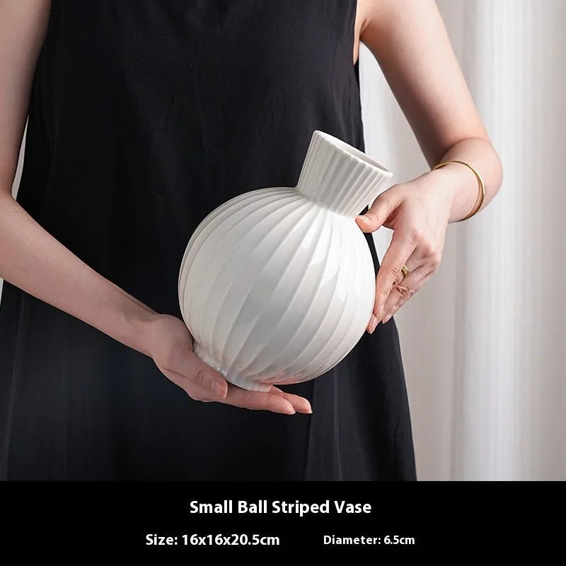 White ceramic ball-shaped vase with striped pattern, shown in small and large sizes with orchid arrangements
