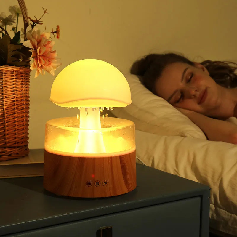 White rain cloud humidifier with falling water droplets and coloured LED lights on nightstand
