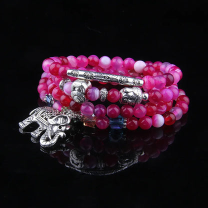 Multi-layer agate amulet bracelet with 6mm beads in blue elephant pattern on a wrist.