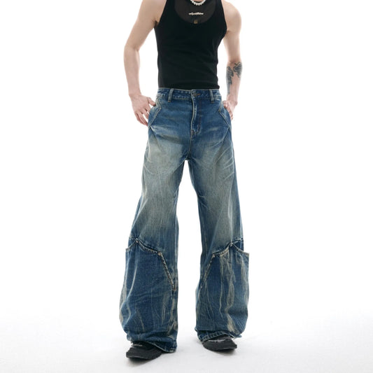 Men's verdant blue jeans with washed burst pattern and curved knife design, showing loose fit and retro style.