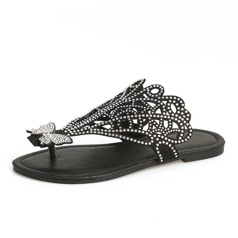 Women's black slip-on flip-toe sandals with rhinestone accents and hollow flat-heeled design on a light background