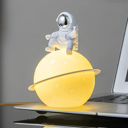 Astronaut planet night lamp in golden finish, 12 cm tall PVC ABS figure with glowing 3 cm orb on 5 cm base