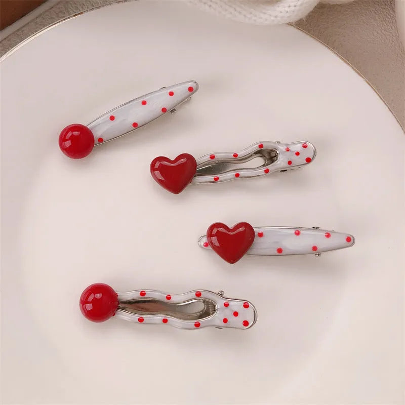 Red plastic hair clip with a 3D love heart and dots on a willow leaf-shaped base.