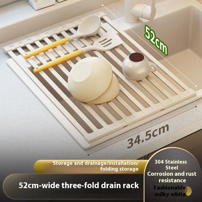 A milky white foldable stainless steel kitchen draining rack collapsed flat beside a kitchen sink.