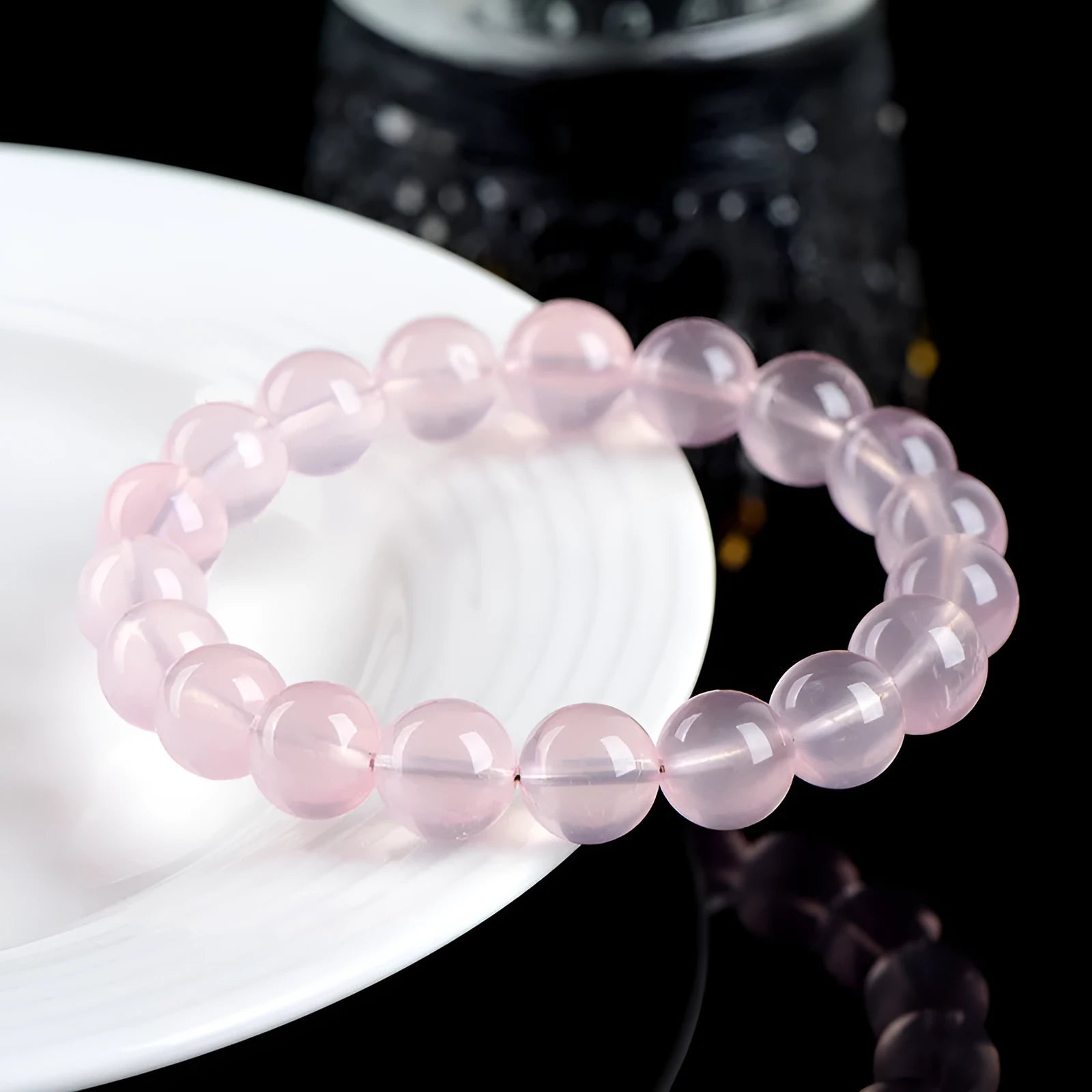 A polished natural starlight crystal round bead bracelet in pink, showing different size options on a wrist.