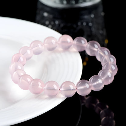 A polished natural starlight crystal round bead bracelet in pink, showing different size options on a wrist.
