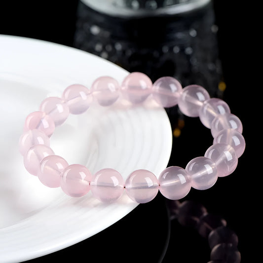 A polished natural starlight crystal round bead bracelet in pink, showing different size options on a wrist.