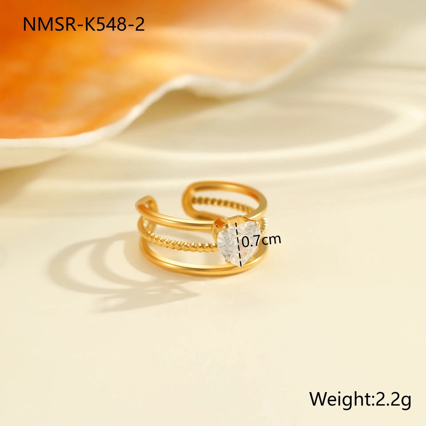 Gold electroplated stainless steel open mouth ring with geometric shapes and zircon inlay on a heart drop.