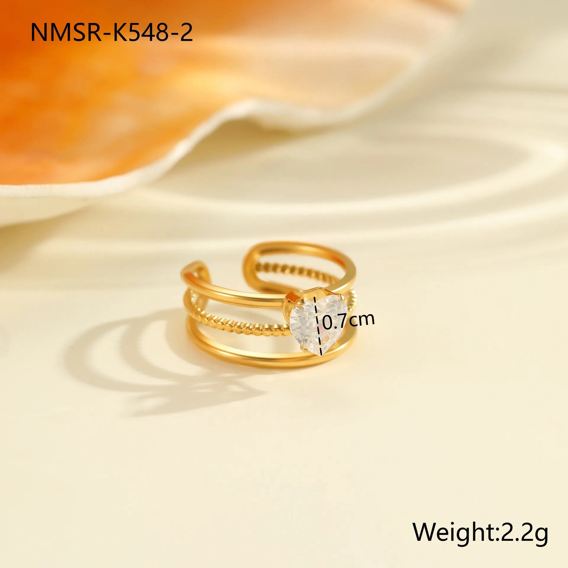Gold electroplated stainless steel open mouth ring with geometric shapes and zircon inlay on a heart drop.