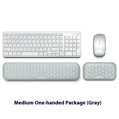 Black and grey memory foam mouse wrist rests with cloth and leather-style covers on a desk.