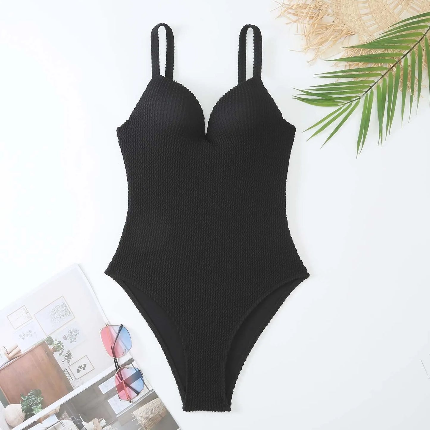 Women's black one-piece swimsuit with a sunken vertical stripe detail, shown on a model, featuring a sleeveless design.