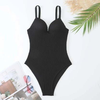 Women's black one-piece swimsuit with a sunken vertical stripe detail, shown on a model, featuring a sleeveless design.
