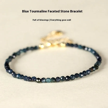 Close-up of a blue tourmaline beaded bracelet with 3mm stones and spacer beads on a wrist.