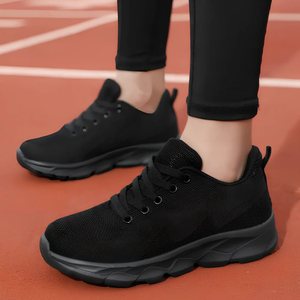 Women's black sneakers with mesh upper, wedge heel, and lace-up front