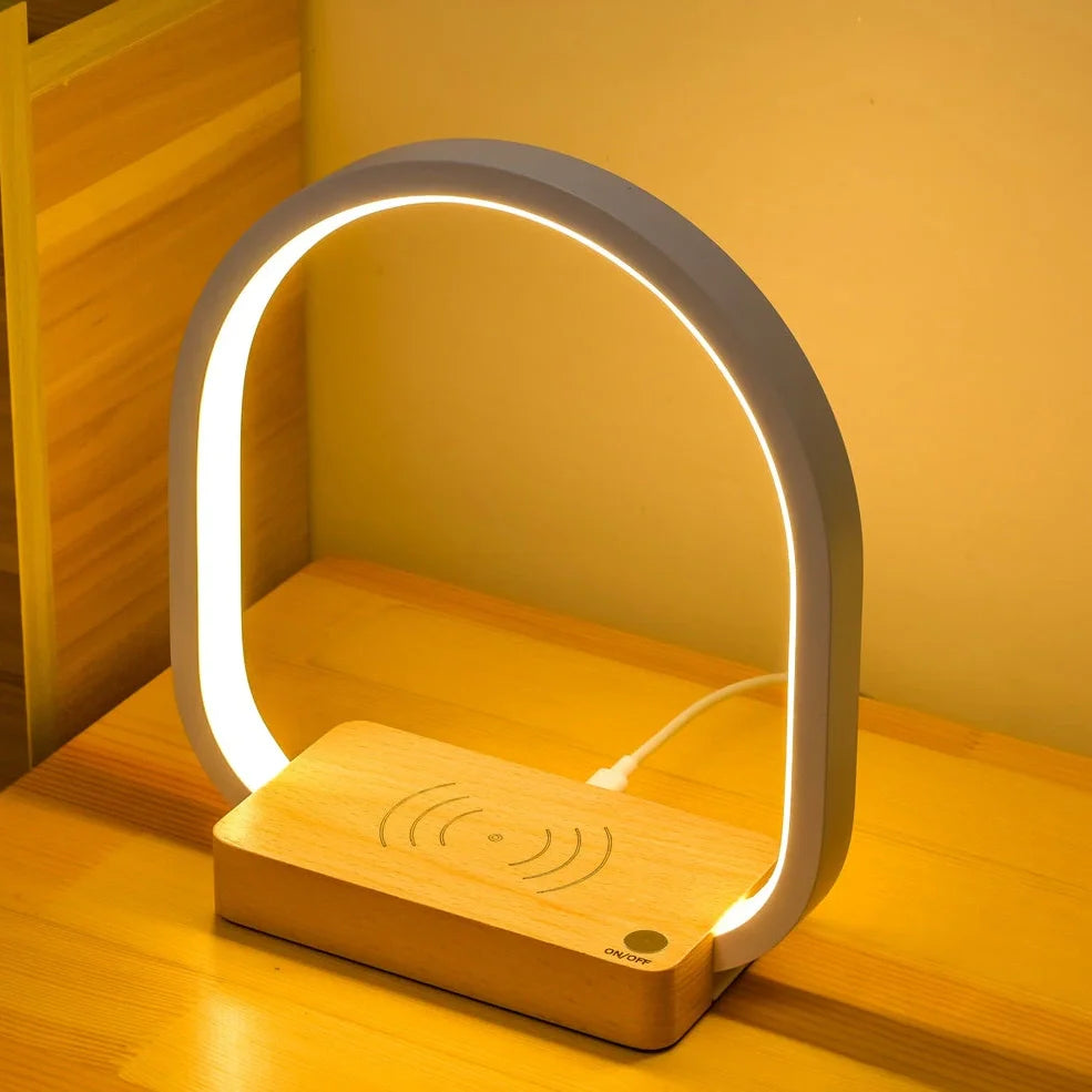 White wireless charging table lamp with metal shade and button switch on wooden surface