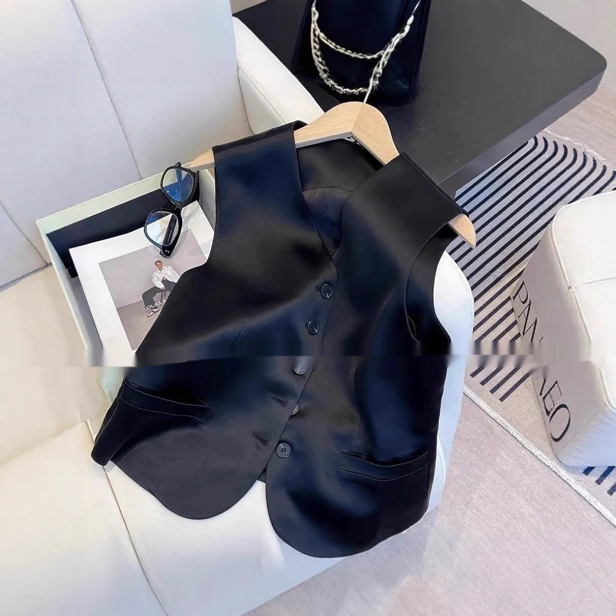 Black satin sleeveless vest for women on a hanger, showing loose fit and splicing detail.