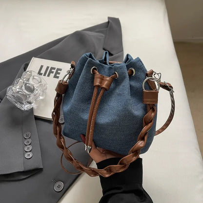 Blue synthetic leather cross body bucket bag with adjustable strap and optional hanging ornaments