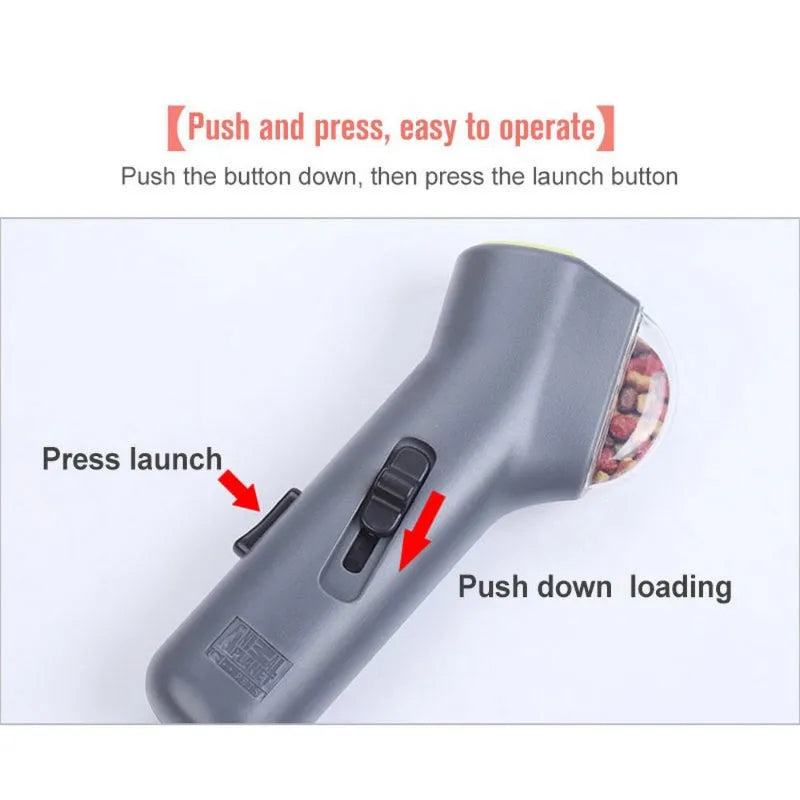 Grey plastic pet snack catapult launcher toy with ergonomic handle, shown with treats.
