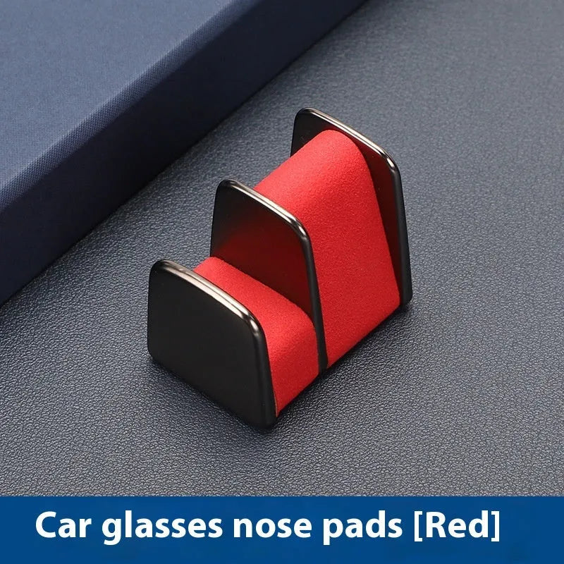 Green zinc alloy and leather glasses clip holder attached to a car dashboard, holding sunglasses.