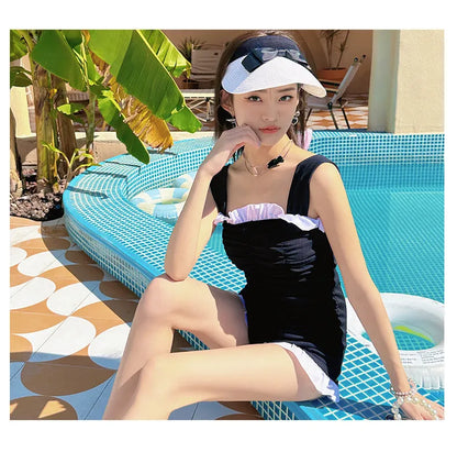 Women's solid colour one-piece swimsuit with suspender straps in pink, green, or black.