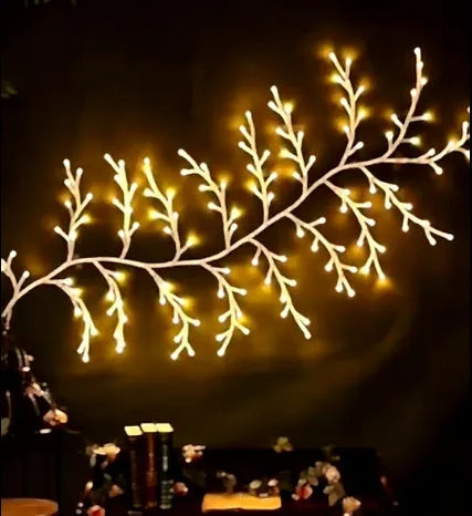 Flexible DIY willow vine LED light garland with warm white lights shaped on a wall.