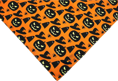 Black and orange reversible Halloween dog bandana with pumpkin and spider web print laid flat
