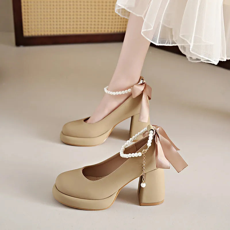 Women's beige Mary Jane shoes with chunky heel, ankle strap, pearl buckle, and round toe on a rubber sole.
