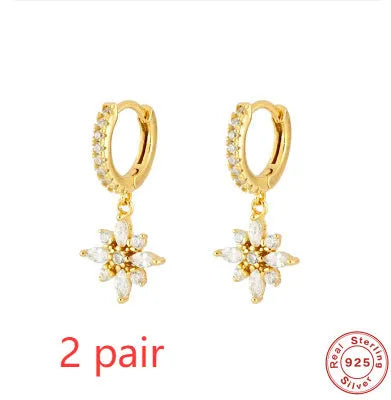 A pair of sterling silver snowflake pendant earrings with cubic zirconia stones on a white background.