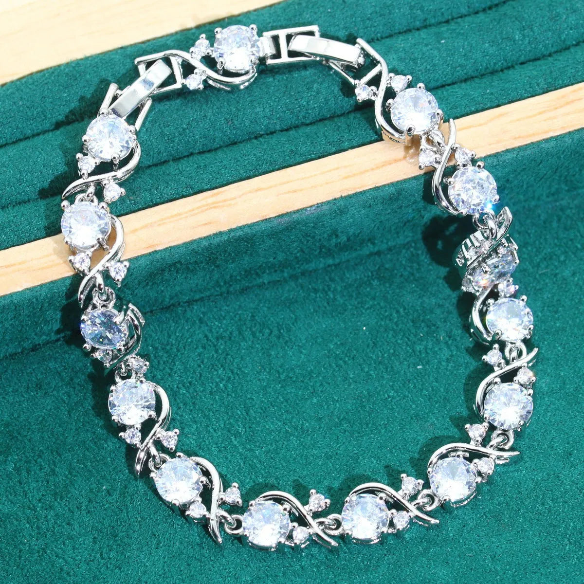 Four-piece bridal jewellery set with zircon pendants on a water wave chain, showing necklace, bracelet, earrings and ring.