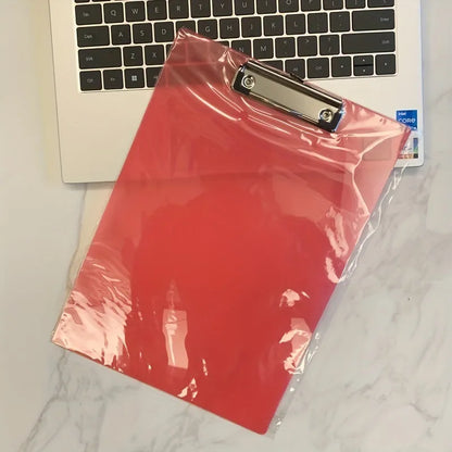 Transparent A4 writing board pad with metal flat clip in blue, alongside A5 size in red on a desk.