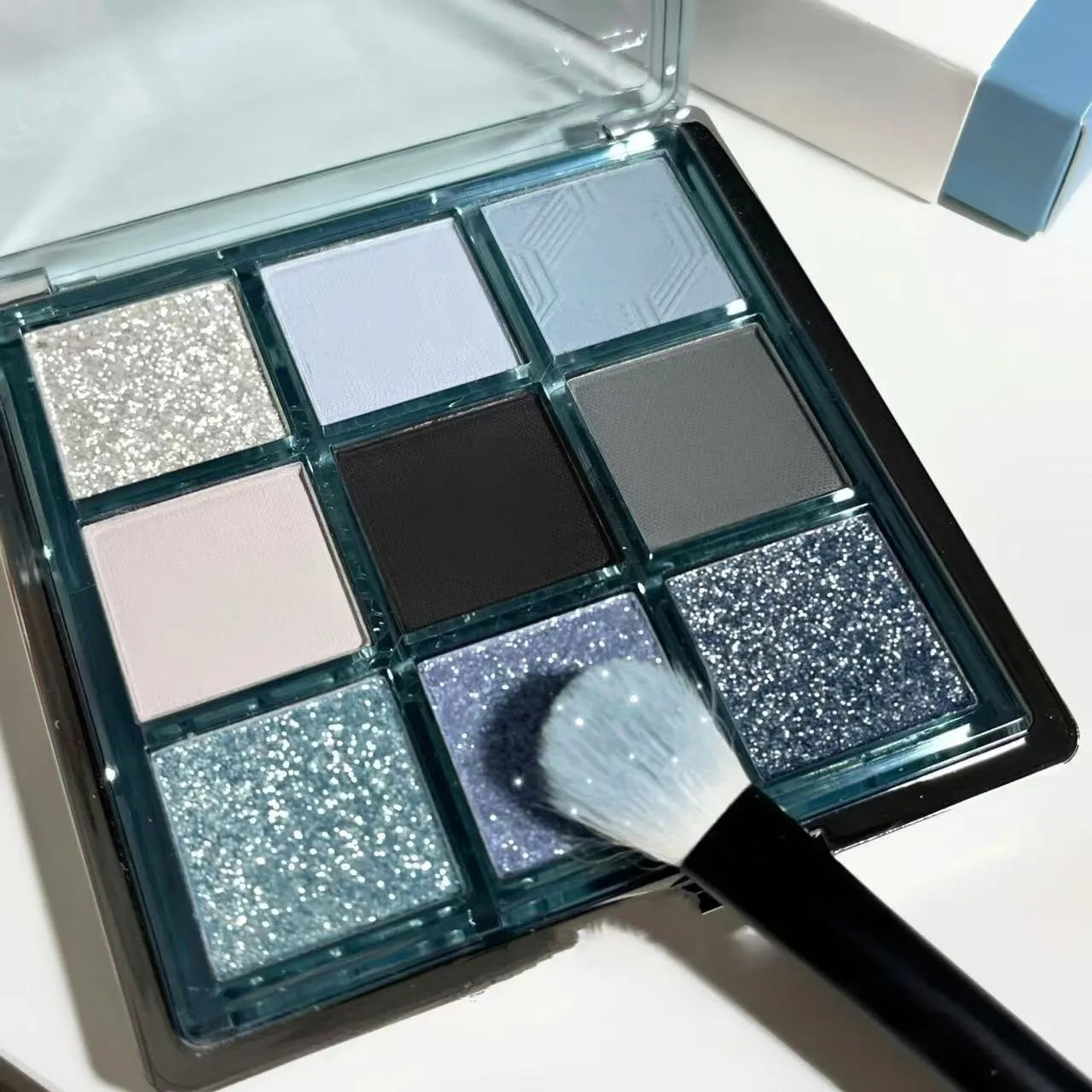 Low saturation blue smoked eye shadow palette with nine colours including matte and shimmer finishes with diamond debris textures