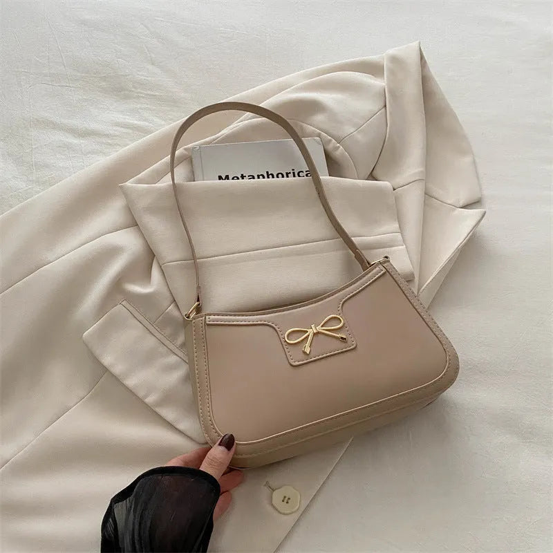 Western style shoulder bag with bow detail in rose pink colour, showing horizontal square shape and single strap.