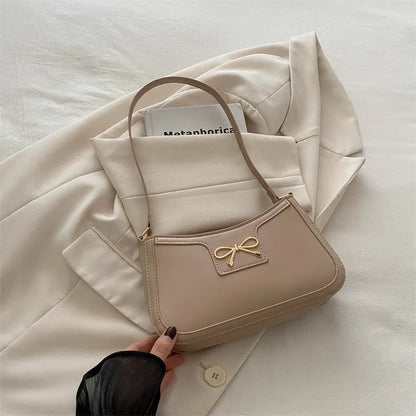 Western style shoulder bag with bow detail in rose pink colour, showing horizontal square shape and single strap.