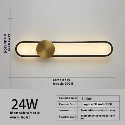 Round black iron wall sconce with integrated LED light glowing on a modern grey wall