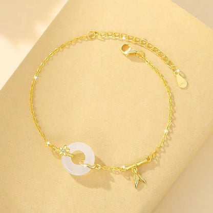 Gold-colour women's bracelet with peace symbol buckle and white chalcedony stone on silver band.