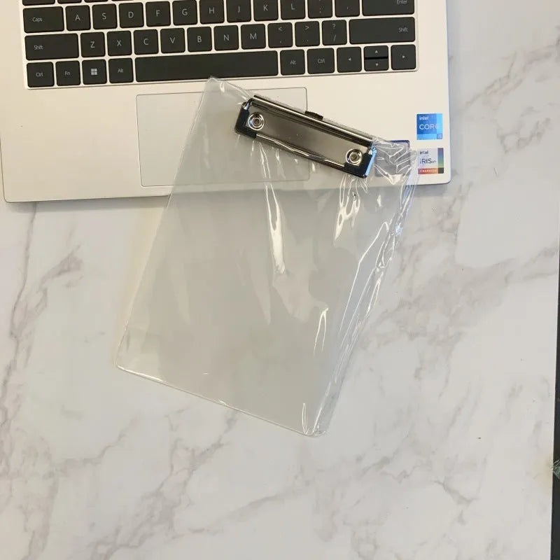 Transparent A4 writing board pad with metal flat clip in blue, alongside A5 size in red on a desk.