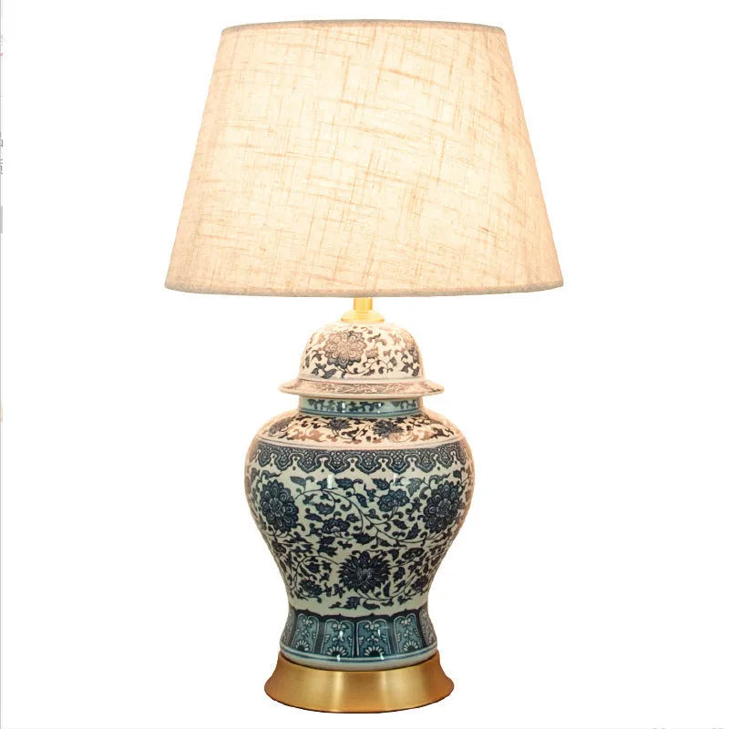 Traditional blue and white Chinese ceramic table lamp with a cloth shade on a bedside table.