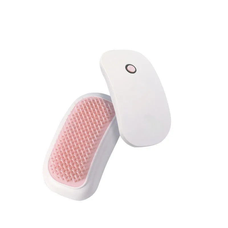 Pink Fuigarry handheld electric pet brush with soft teeth, placed on a carpet next to a cat.